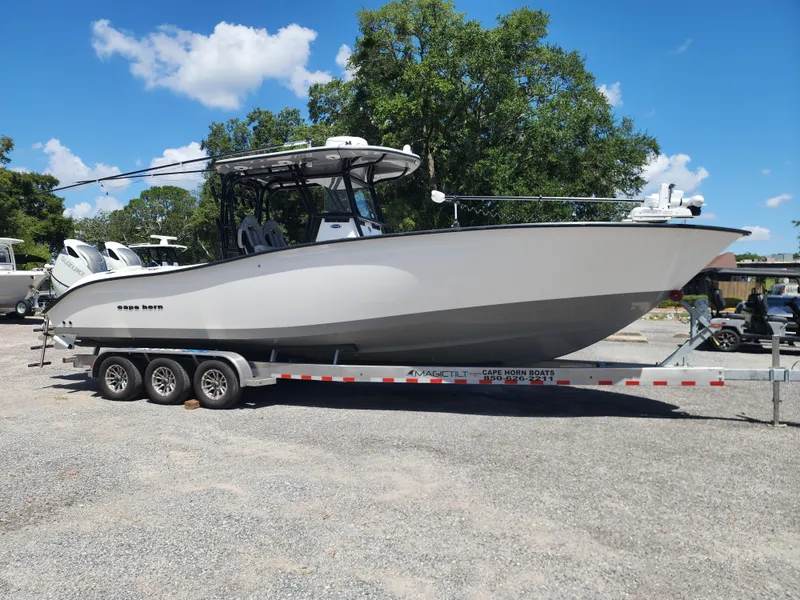 Slide: The Image of 2025 Cape Horn 32 XS boat on trailer, parked outdoors under clear blue sky. - 7