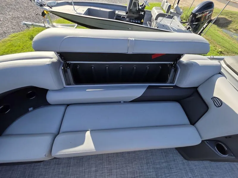 Slide: The Image of 2026 Sun Tracker Party Barge 20 DLX storage compartment with open seat cushion. - 10