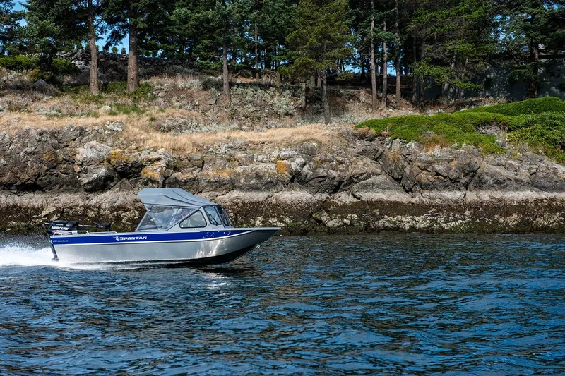 Slide: The Image of 2025 Spartan 20 Areus boat cruising near rocky shoreline with trees in the background. - 10