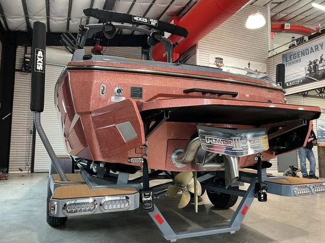 Slide: The Image of 2024 Axis Wake Research A225 boat in showroom, rear view showcasing propeller and design features. - 13