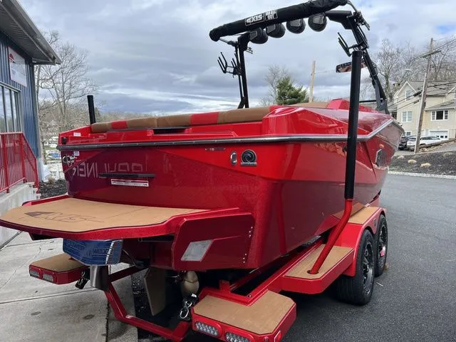 Slide: The Image of 2024 Axis Wake Research T235 boat in vibrant red on a trailer, parked outdoors. - 3