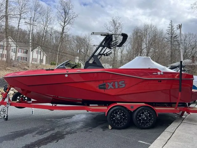 Slide: The Image of 2024 Axis Wake Research T235 boat in vibrant red on a trailer, parked outdoors. - 9