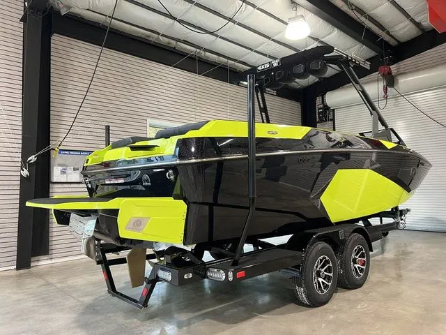 Slide: The Image of 2024 Axis Wake Research A245 boat in black and neon yellow, displayed indoors on a trailer. - 4
