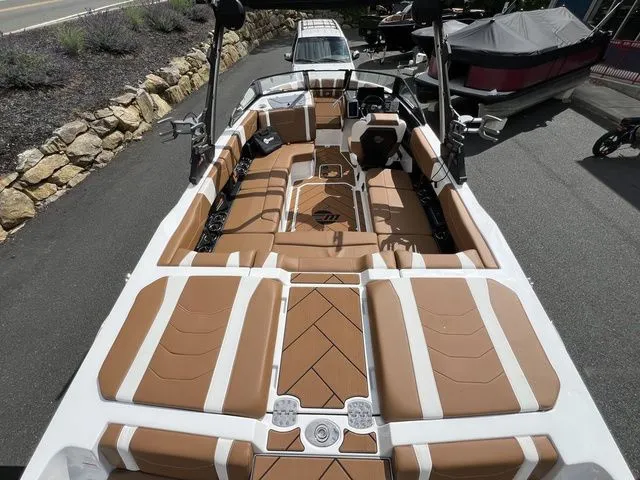 Slide: The Image of 2024 Malibu 23 LSV boat with luxurious tan and white seating, docked outdoors. - 5