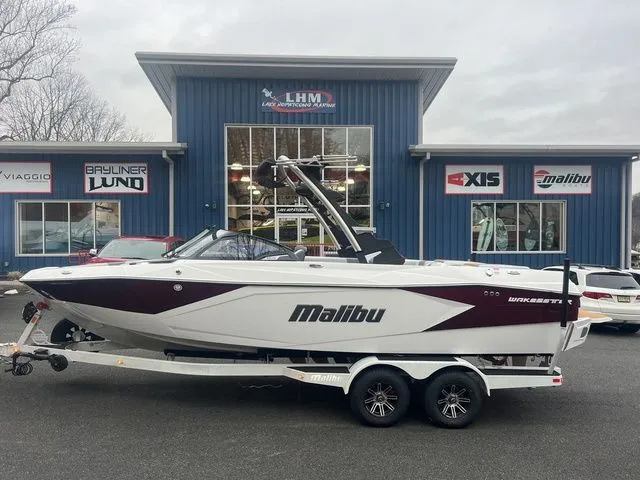 Slide: The Image of 2024 Malibu 23 LSV boat on trailer outside dealership, showcasing sleek design and modern features. - 1