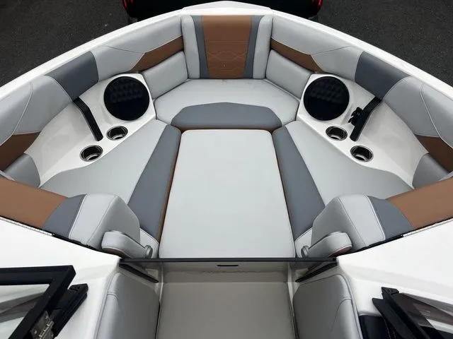 Slide: The Image of 2024 Malibu 23 LSV boat interior with gray and brown seating, cup holders, and speakers. - 12