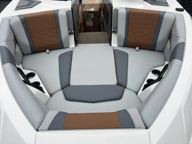 Slide: The Image of 2024 Malibu 23 LSV boat interior with gray and brown seating, cup holders, and modern design. - 14