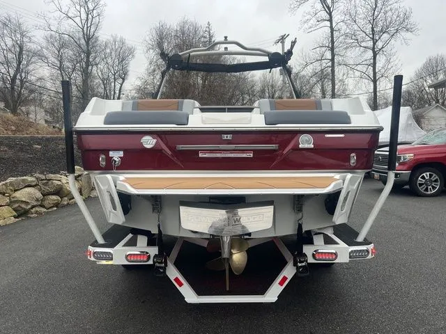 Slide: The Image of 2024 Malibu 23 LSV boat, rear view, parked on asphalt, overcast day. - 5