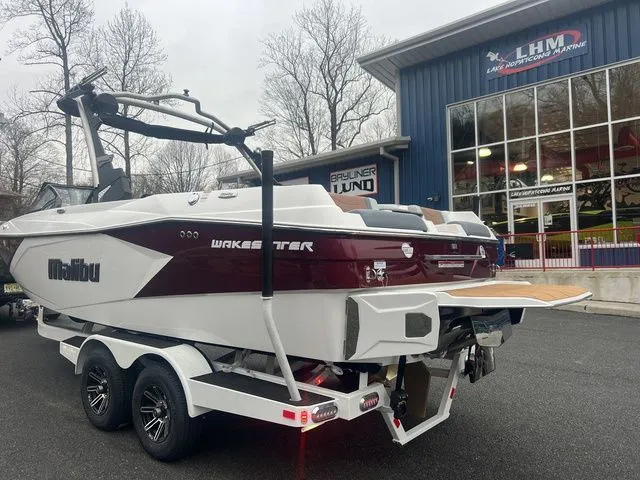 Slide: The Image of 2024 Malibu 23 LSV boat on trailer outside dealership, showcasing sleek design and modern features. - 8