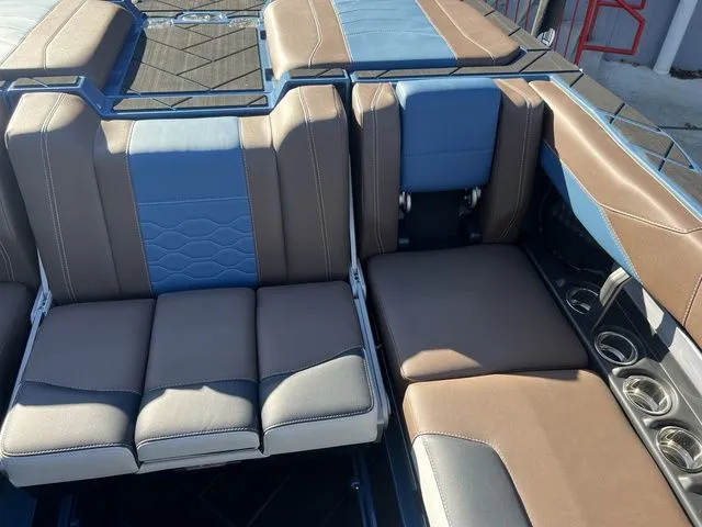 Slide: The Image of 2024 Malibu 23 LSV boat interior with blue and brown seating, cup holders visible. - 11