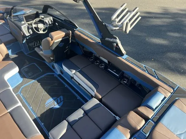 Slide: The Image of 2024 Malibu 23 LSV boat interior with brown and blue seating, modern dashboard, and spacious layout. - 7