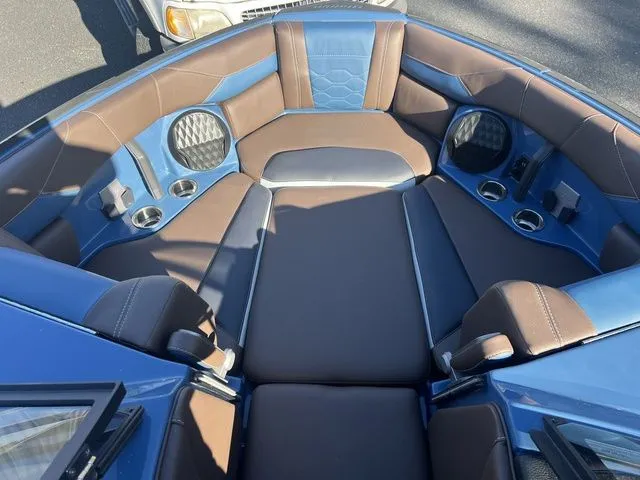 Slide: The Image of 2024 Malibu 23 LSV boat interior with blue and brown seating, cup holders, and speakers. - 8