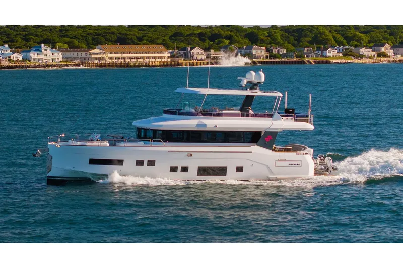 Slide: The Image of 2019 Sirena 64 yacht cruising near coastal town, clear blue water, sunny day. - 100