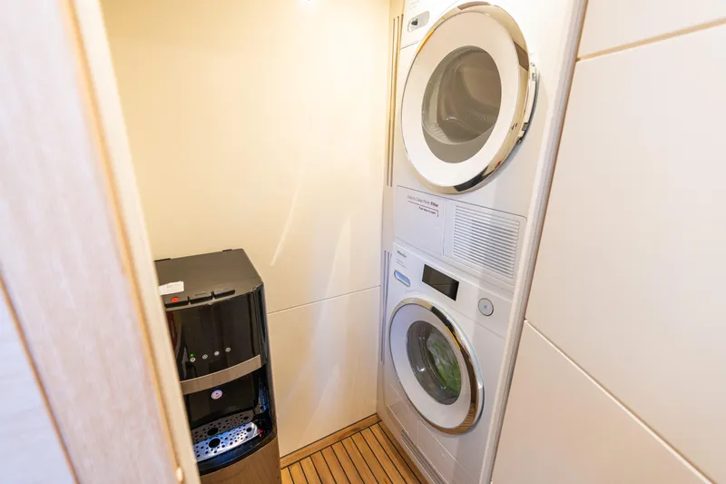 Slide: The Image of Laundry area in 2019 Sirena 64 yacht with washer, dryer, and water dispenser. - 73
