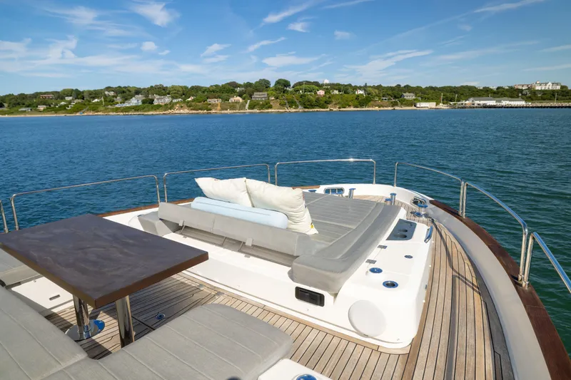 Slide: The Image of Luxurious 2019 Sirena 64 yacht deck with sun loungers and table, overlooking serene coastal waters. - 75