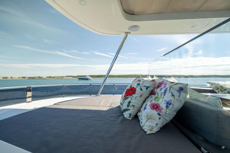 Slide: The Image of Luxurious 2019 Sirena 64 yacht deck with floral cushions, overlooking serene ocean view. - 83