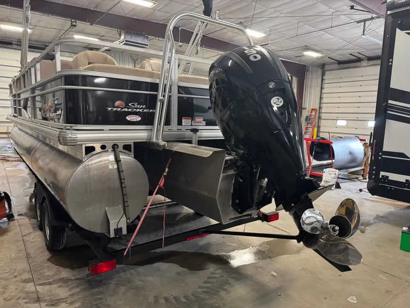 Slide: The Image of 2019 Sun Tracker SportFish 22 XP3 pontoon boat in a garage, featuring a powerful outboard motor. - 4