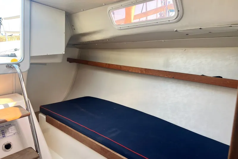 Slide: The Image of 2005 J Boats J/100 interior cabin with blue cushion and wooden accents. - 20