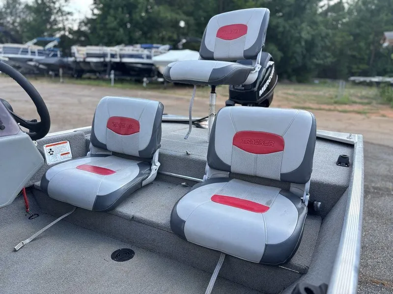 Slide: The Image of 2013 Tracker Pro 160 boat seats with red and gray upholstery, parked outdoors. - 14
