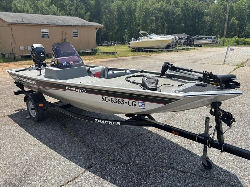 Slide: The Image of 2013 Tracker Pro 160 boat on trailer, parked outdoors near a wooden building. - 2
