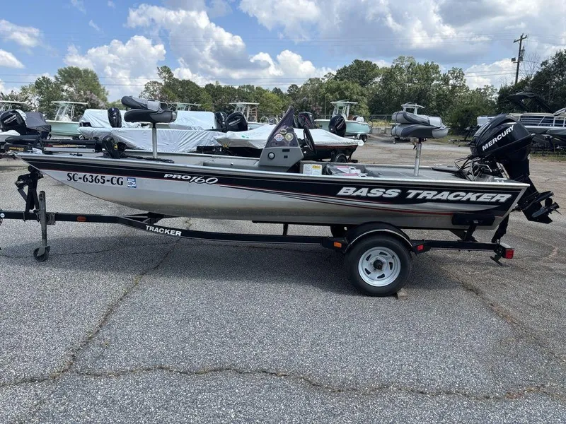 Slide: The Image of 2013 Tracker Pro 160 Bass boat on trailer, parked outdoors under cloudy sky. - 4