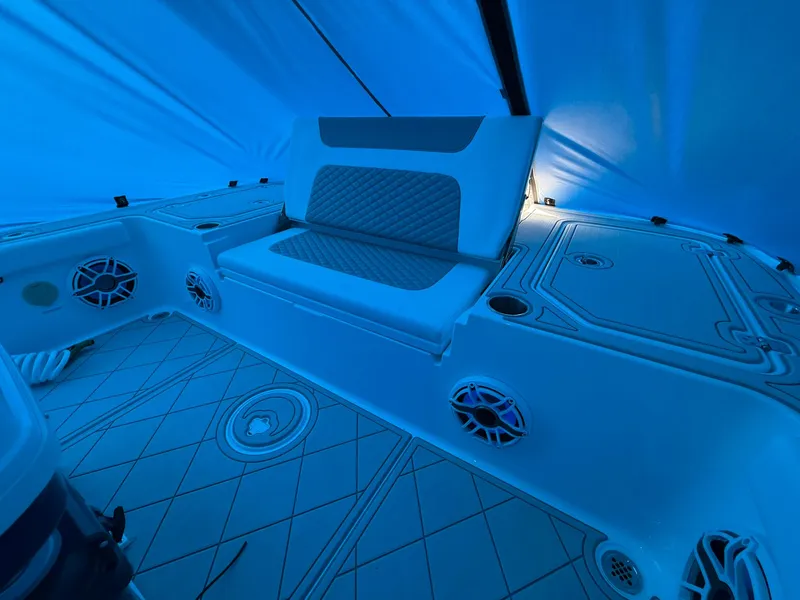 Slide: The Image of 2024 Caymas 28 HB boat interior with seating and speakers under blue lighting. - 13