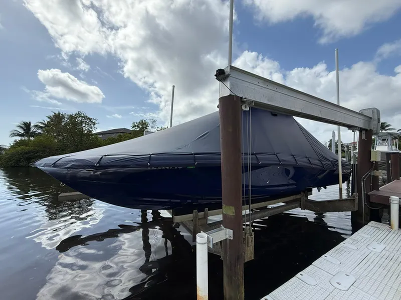 Slide: The Image of 2024 Caymas 28 HB boat covered and docked on a lift under a cloudy sky. - 16