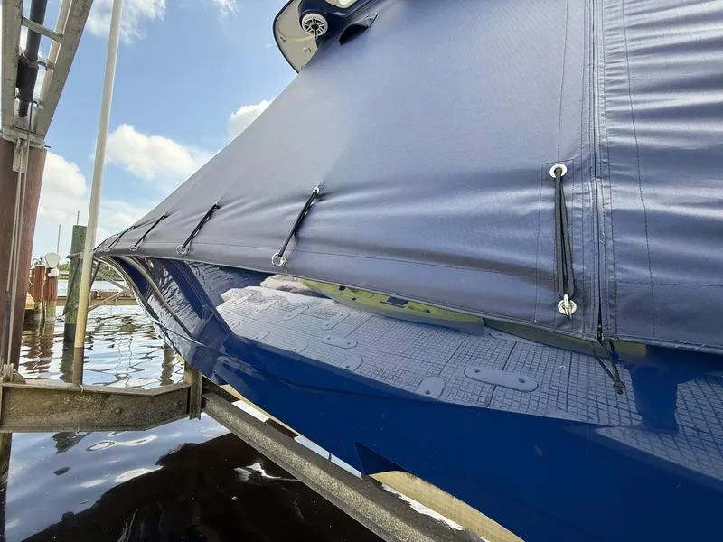 Slide: The Image of 2024 Caymas 28 HB boat with protective cover, docked on a sunny day. - 3