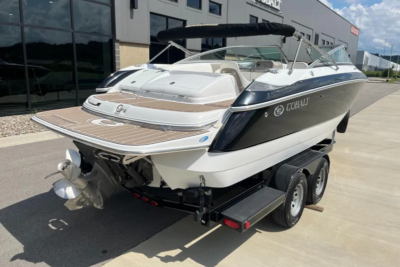 Slide: The Image of 2006 Cobalt 240 boat on trailer, parked outside a building on a sunny day. - 4