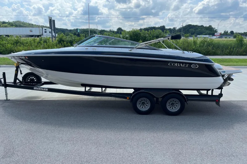 Slide: The Image of 2006 Cobalt 240 boat on trailer, parked outdoors under cloudy sky. - 6