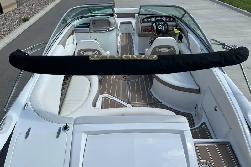Slide: The Image of 2006 Cobalt 240 boat interior with white seating and wood accents, docked on pavement. - 9