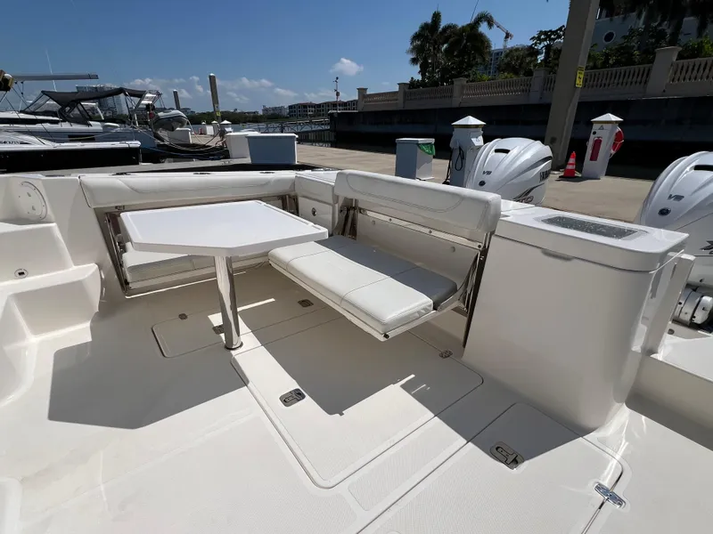 Slide: The Image of 2023 Pursuit OS 355 Offshore boat interior with seating and table, docked under clear skies. - 13