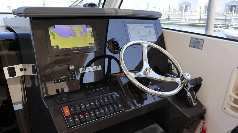 Slide: The Image of 2023 Pursuit OS 355 Offshore helm with navigation screens and steering wheel. - 33