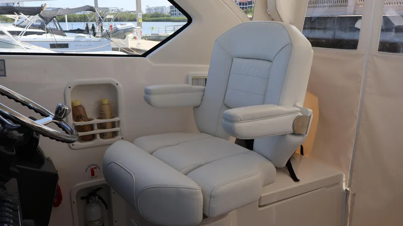 Slide: The Image of Captain's chair in 2023 Pursuit OS 355 Offshore boat cockpit, featuring luxurious white upholstery. - 36
