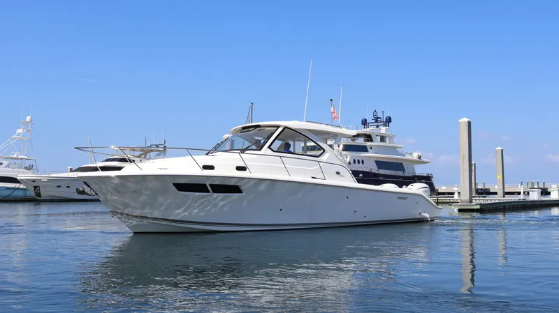 Slide: The Image of 2023 Pursuit OS 355 Offshore yacht docked in a marina under clear blue skies. - 4