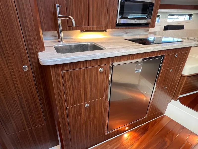 Slide: The Image of 2023 Pursuit OS 355 Offshore yacht kitchen with wood cabinetry, sink, and modern appliances. - 49