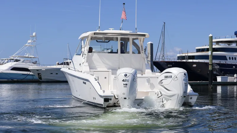 Slide: The Image of 2023 Pursuit OS 355 Offshore boat with twin Yamaha engines in a marina. - 5