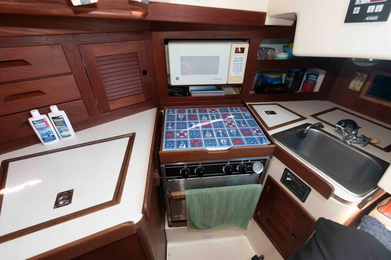 Slide: The Image of 1994 Tartan 31 yacht kitchen with stove, microwave, sink, and storage cabinets. - 15