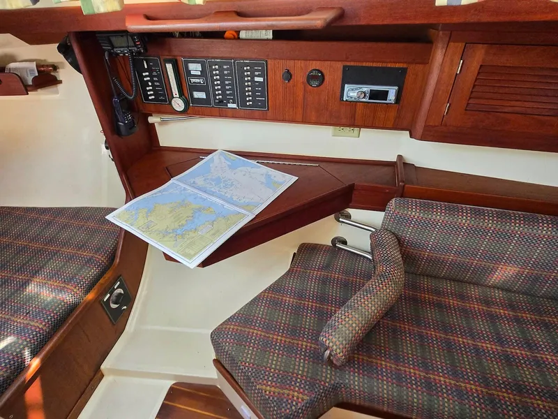Slide: The Image of Navigation station inside a 1994 Tartan 31 sailboat with nautical charts and control panel. - 16