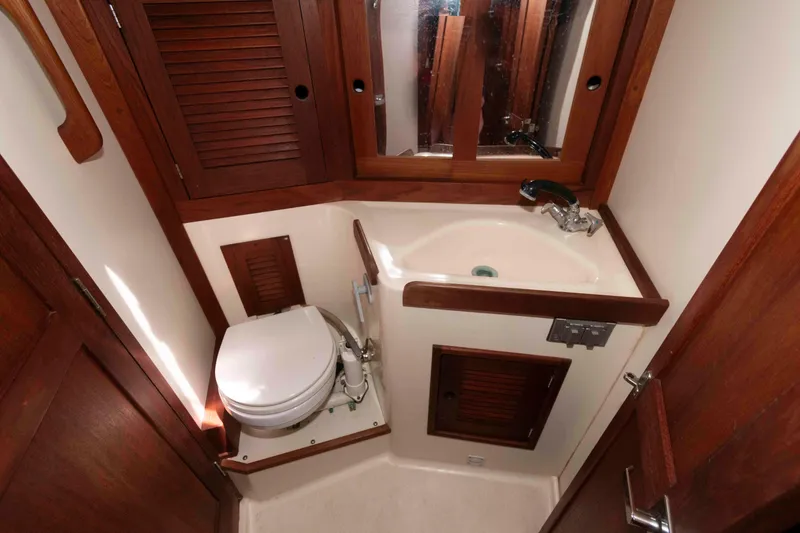 Slide: The Image of Compact bathroom in a 1994 Tartan 31 sailboat with wooden cabinetry and white fixtures. - 19