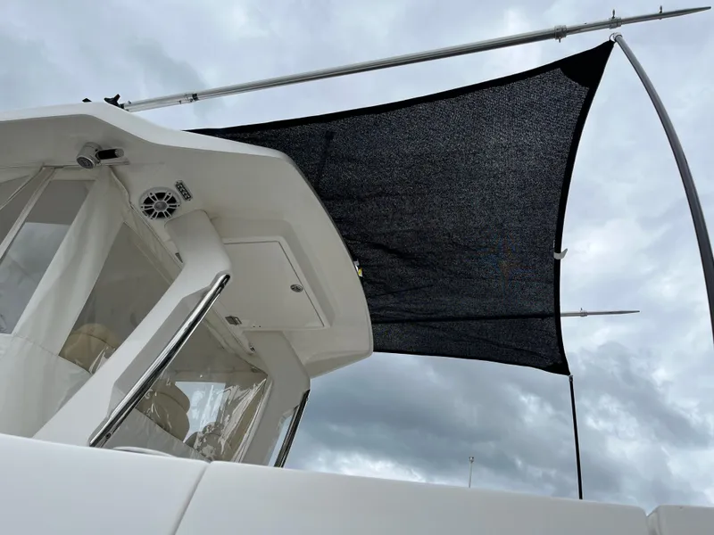 Slide: The Image of 2022 Regal 33 SAV boat with black sunshade against cloudy sky. - 33