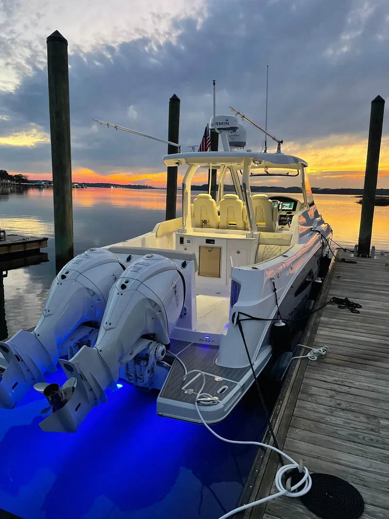 Slide: The Image of 2022 Regal 33 SAV boat docked at sunset with blue underwater lights. - 42