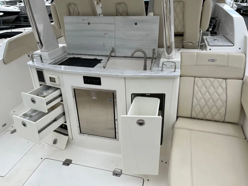 Slide: The Image of 2022 Regal 33 SAV boat interior with kitchenette, storage drawers, and seating. - 7