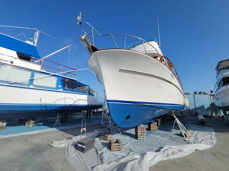 Slide: The Image of 1977 CHB 34 boat on dry dock, blue and white hull, clear sky background. - 43