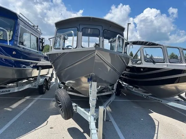 Slide: The Image of 2025 Spartan 220 Maximus Pro boat on trailer, parked between two other boats. - 3