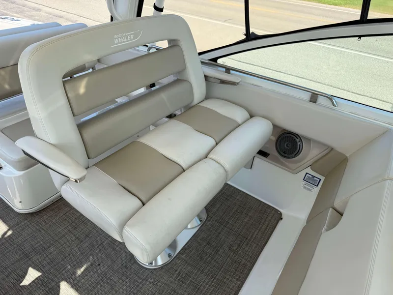 Slide: The Image of 2017 Boston Whaler 320 Vantage interior seating with beige upholstery and speaker. - 18