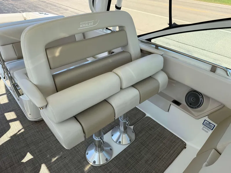 Slide: The Image of 2017 Boston Whaler 320 Vantage interior seating with beige upholstery and stainless steel fixtures. - 19