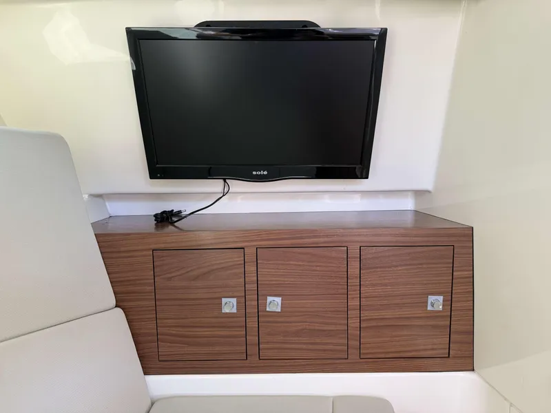 Slide: The Image of 2017 Boston Whaler 320 Vantage interior with TV and wooden storage cabinets. - 22