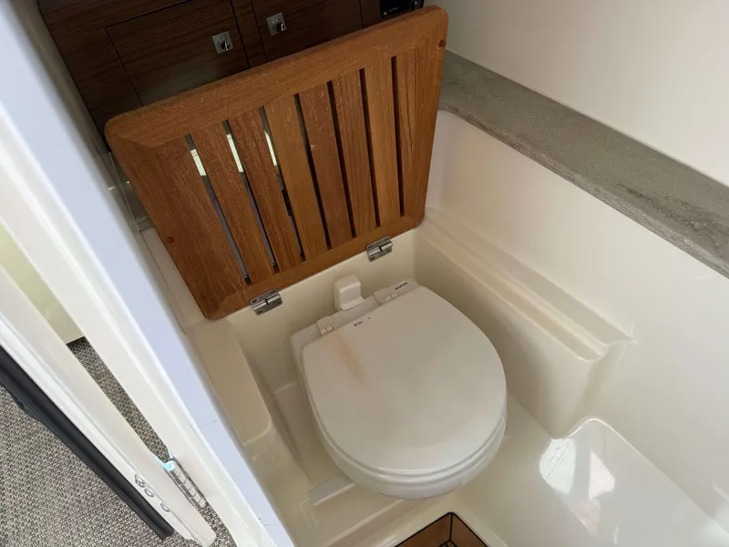 Slide: The Image of 2017 Boston Whaler 320 Vantage boat interior with wooden seat cover over toilet. - 35