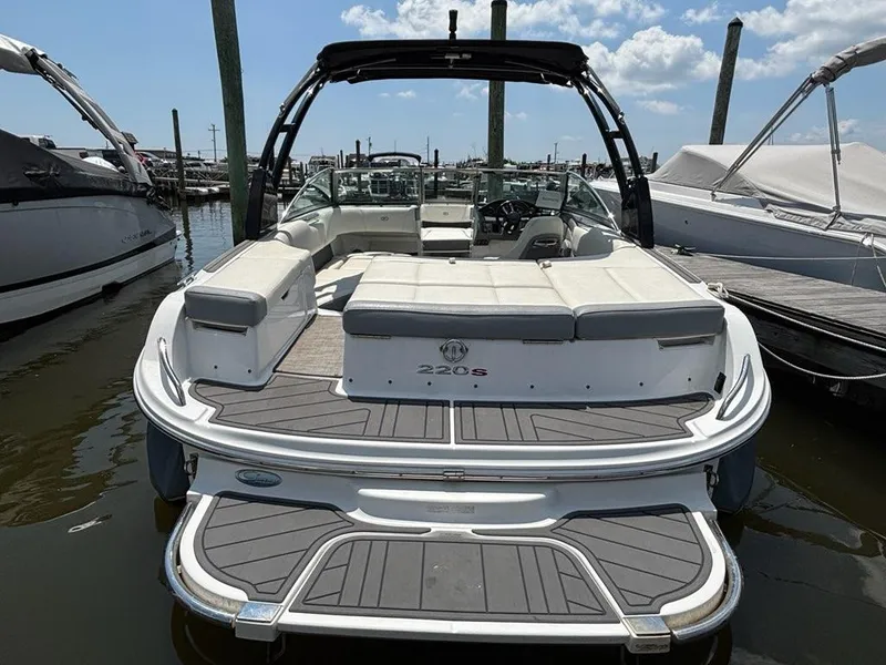 Slide: The Image of 2019 Cobalt 220S boat docked, featuring spacious seating and sleek design under a clear sky. - 2